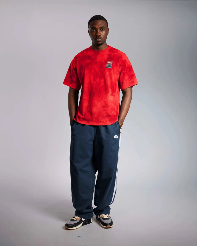 Front view of a model wearing the washed red Patta x Nike NRG T-shirt with navy track pants.