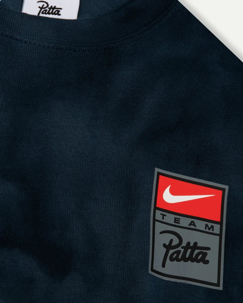 Close-up of the Patta x Nike washed blue t-shirt featuring the Team Patta chest logo badge.