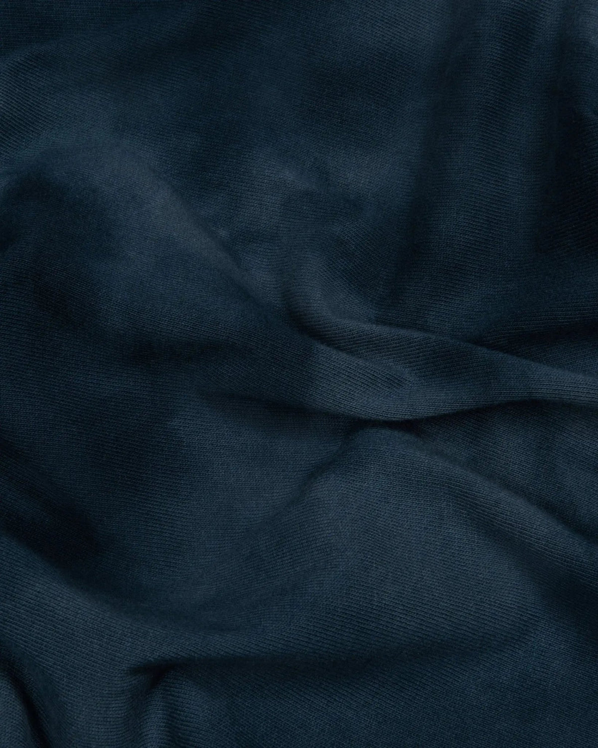Close-up of the washed dark blue tie-dye cotton fabric texture on the Patta x Nike NRG T-shirt.