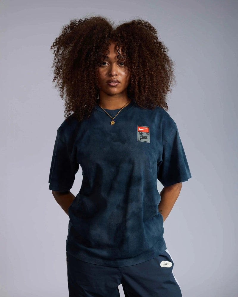 Female model wears the dark blue washed Patta x Nike NRG T-shirt with chest badge.