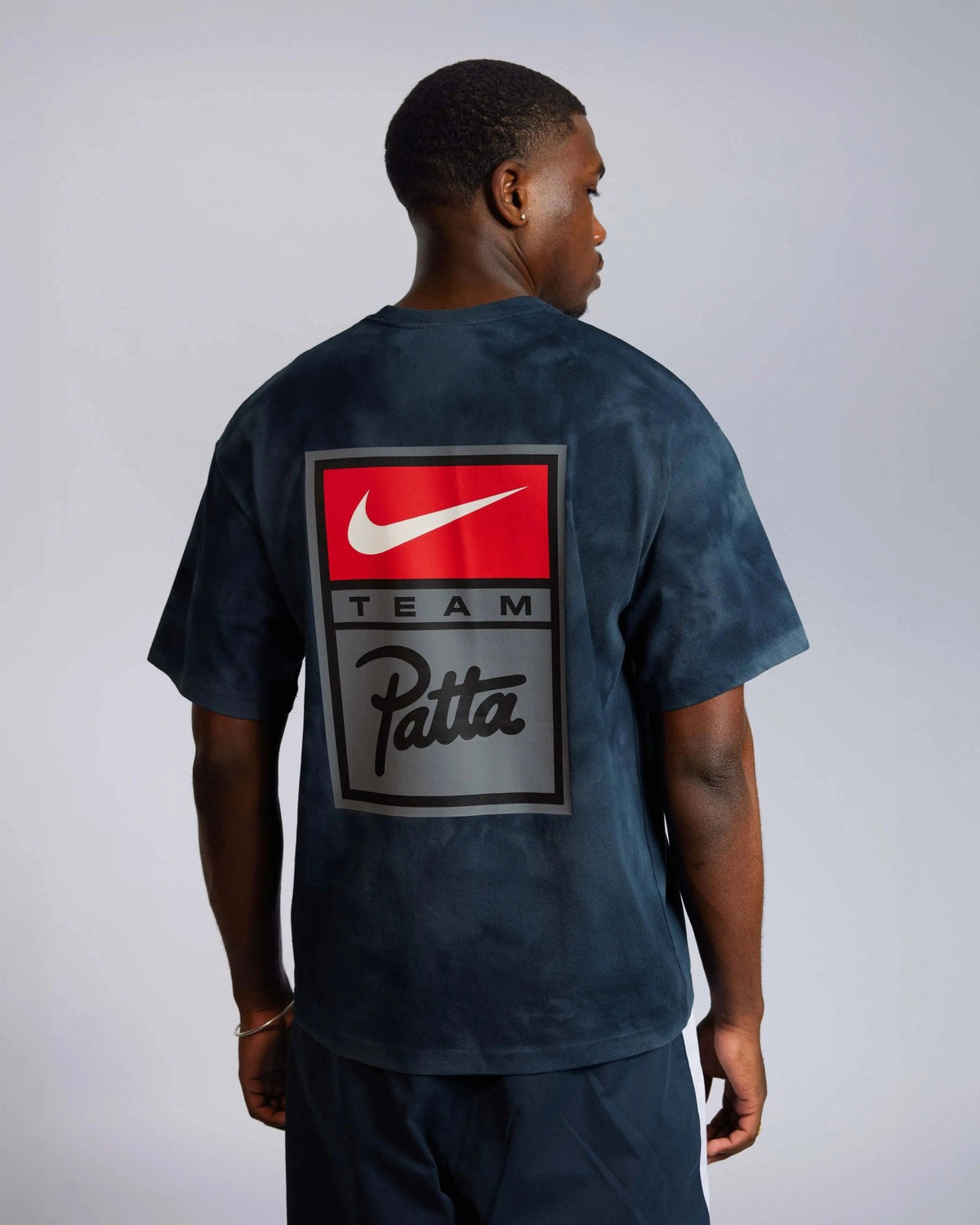 Back view of model wearing Patta x Nike washed dark blue t-shirt with back graphic.
