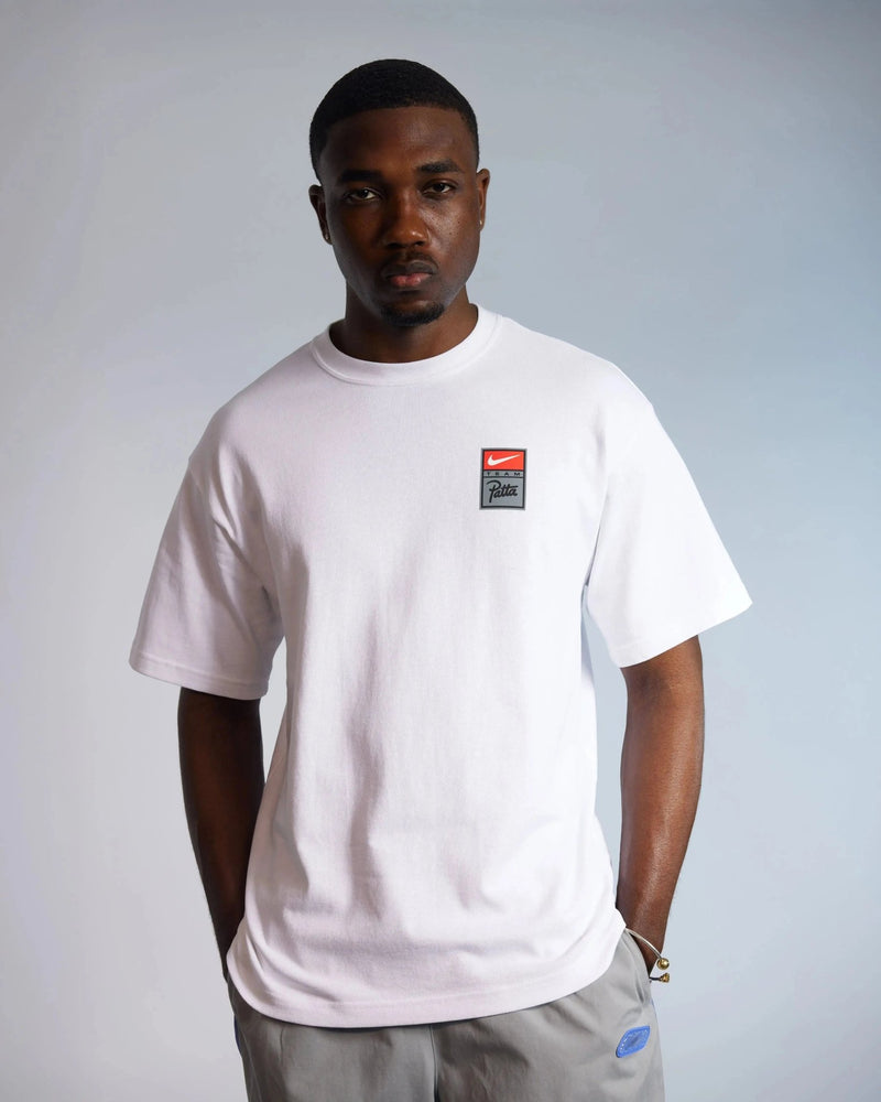 Model wearing the white Patta x Nike NRG heavyweight cotton t-shirt with a chest logo badge.