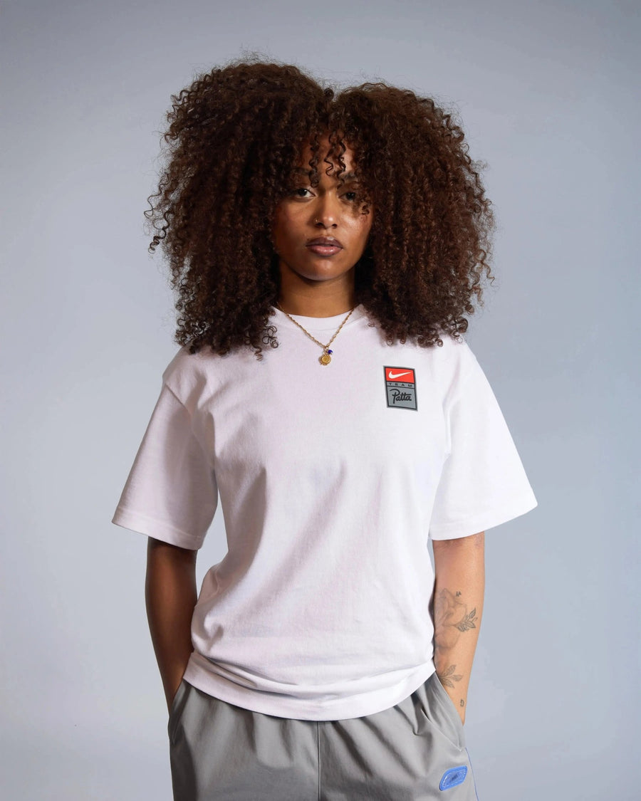 Female model wearing the white Patta x Nike NRG cotton T-shirt with chest logo badge.