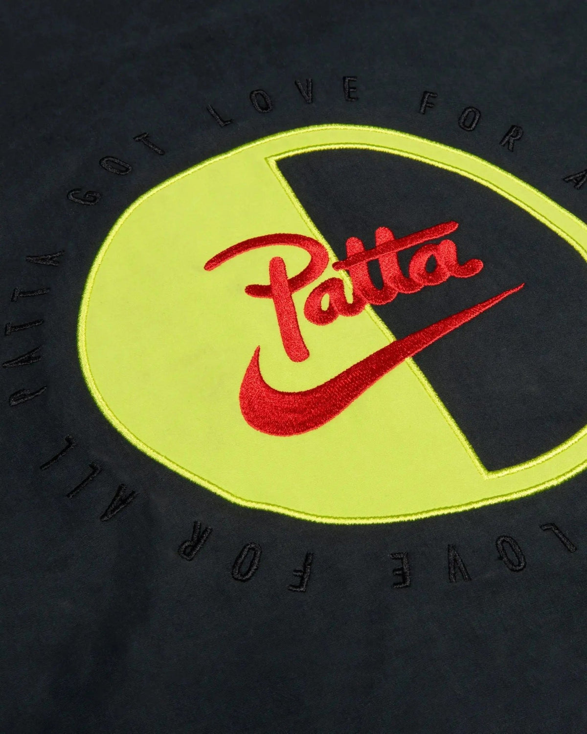 Close-up of the red embroidered Patta Nike logo and cyber applique on the black NRG track jacket.