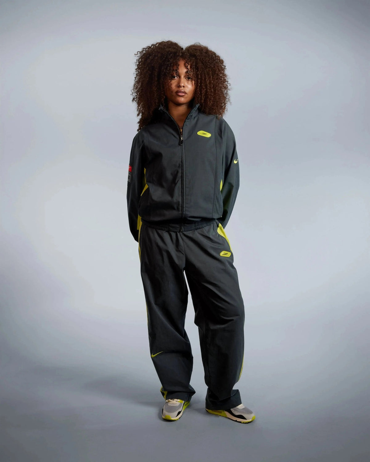 Model wearing the black and cyber Patta x Nike NRG track jacket with matching track pants.