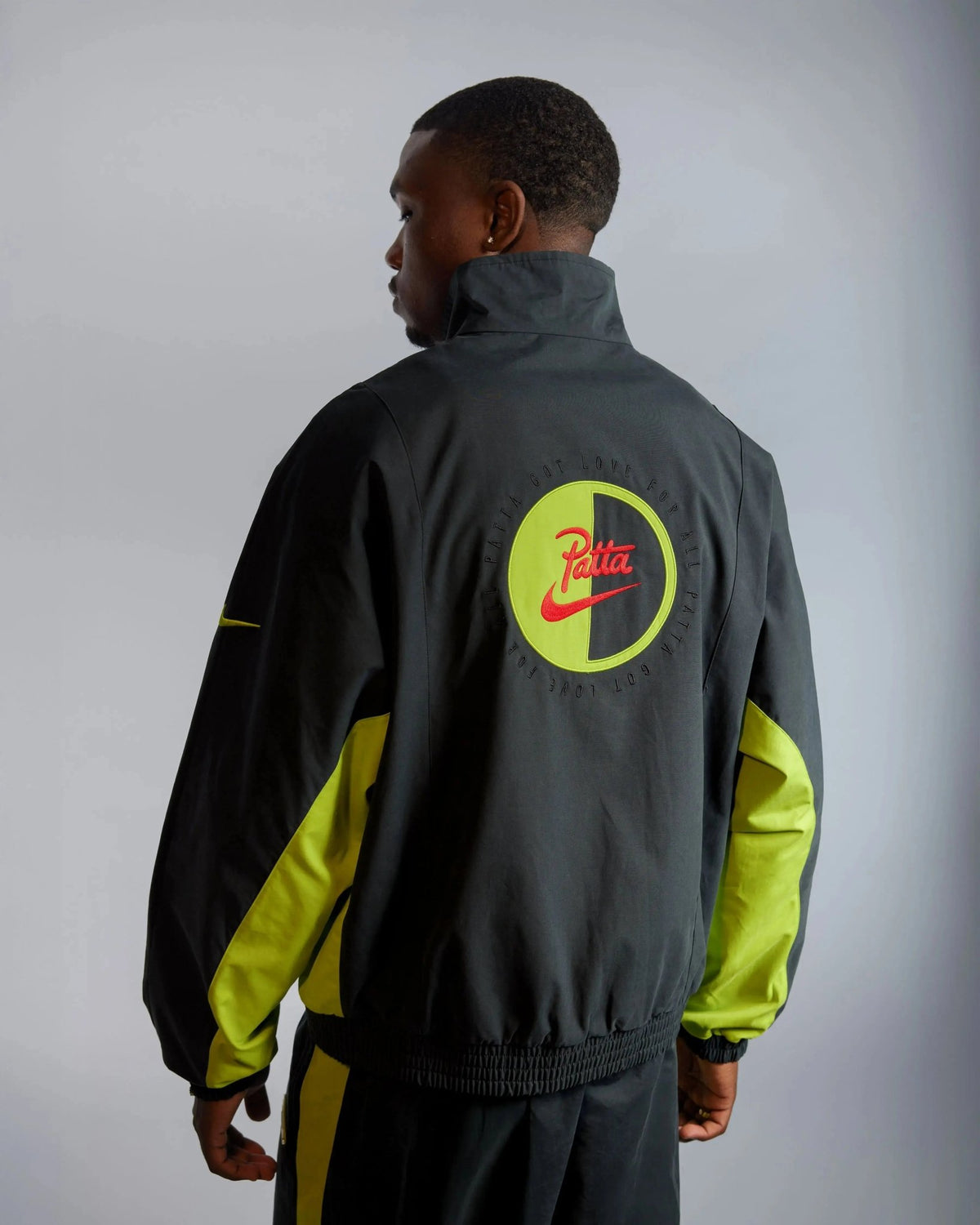 Patta x Nike NRG Track Jacket in black and cyber with back embroidered logo worn by a model.