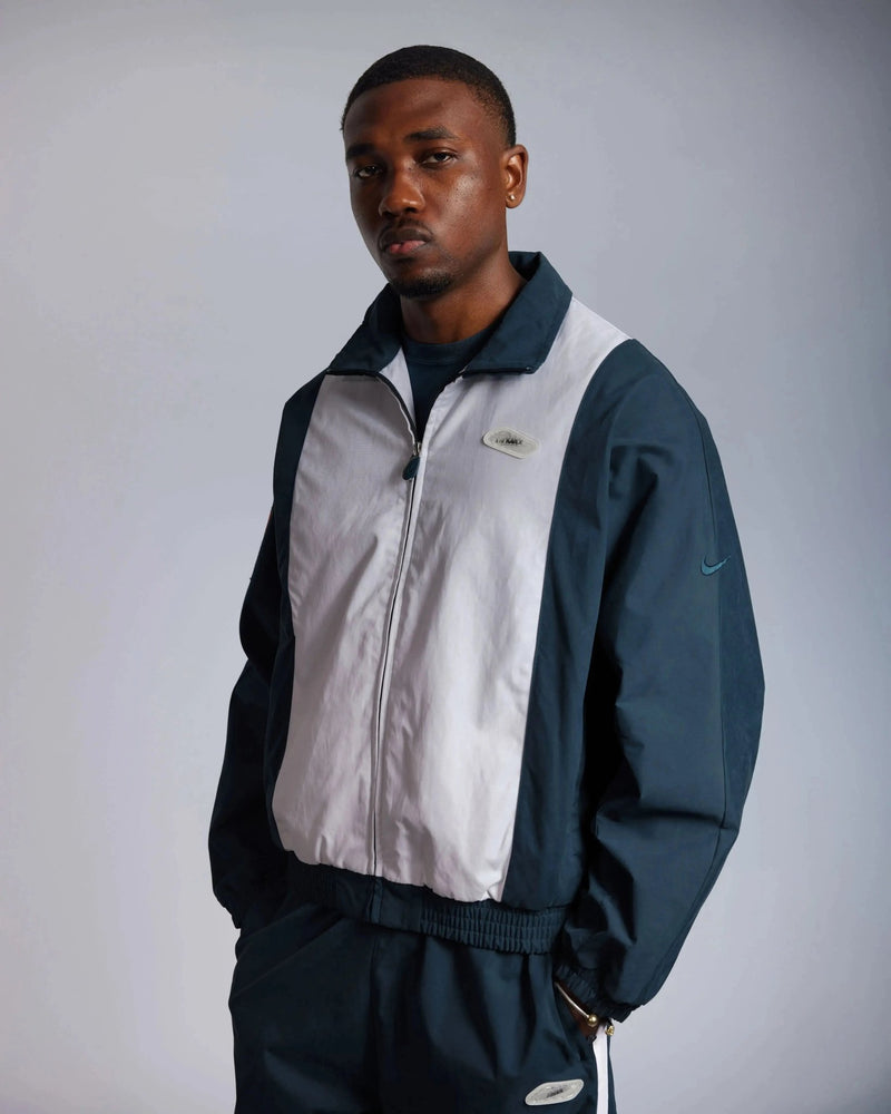 Front view of a model wearing the Patta x Nike NRG Track Jacket in Deep Ocean and White.