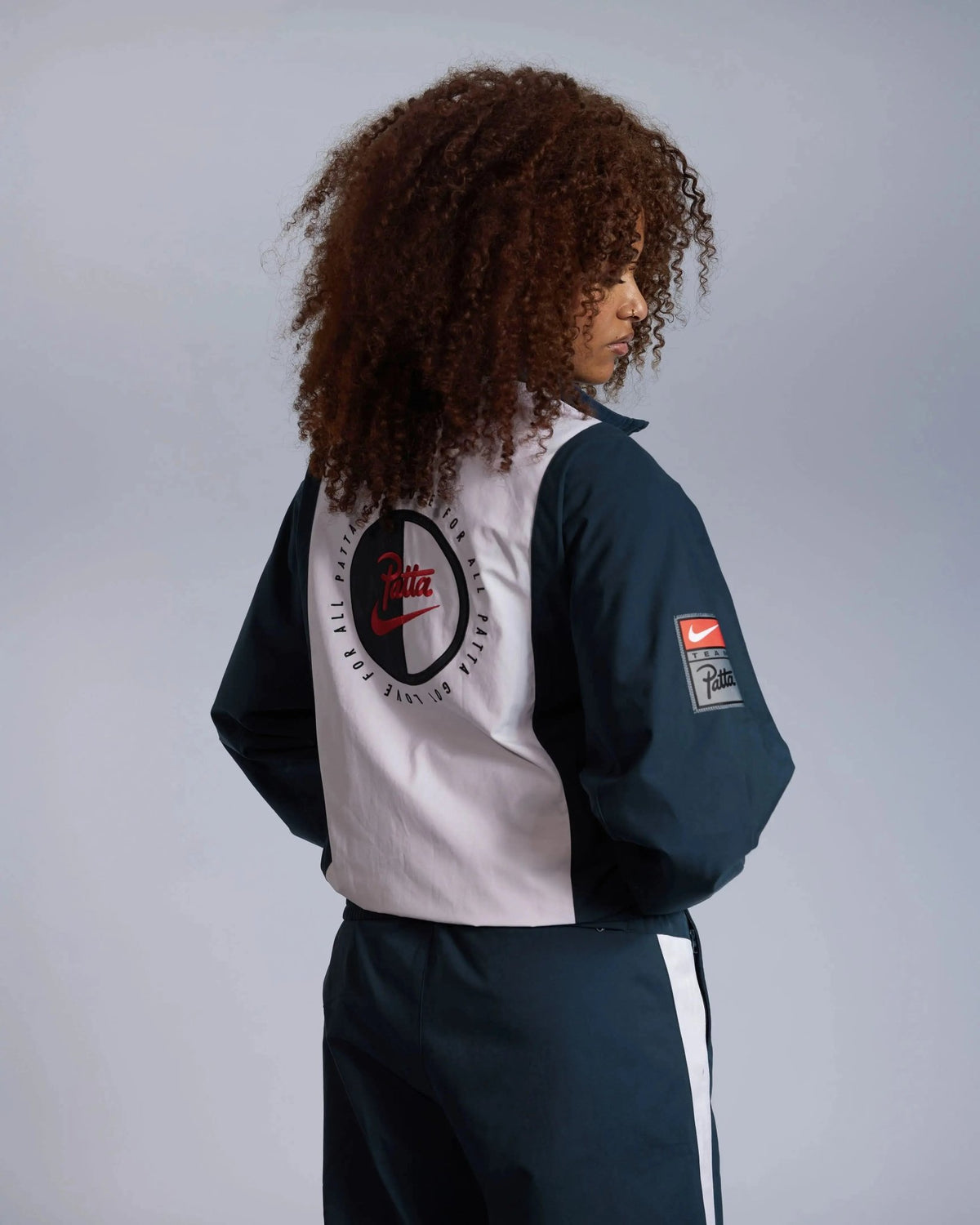 Patta x Nike NRG Track Jacket in deep ocean and white, showing the embroidered circular back graphic on a model.