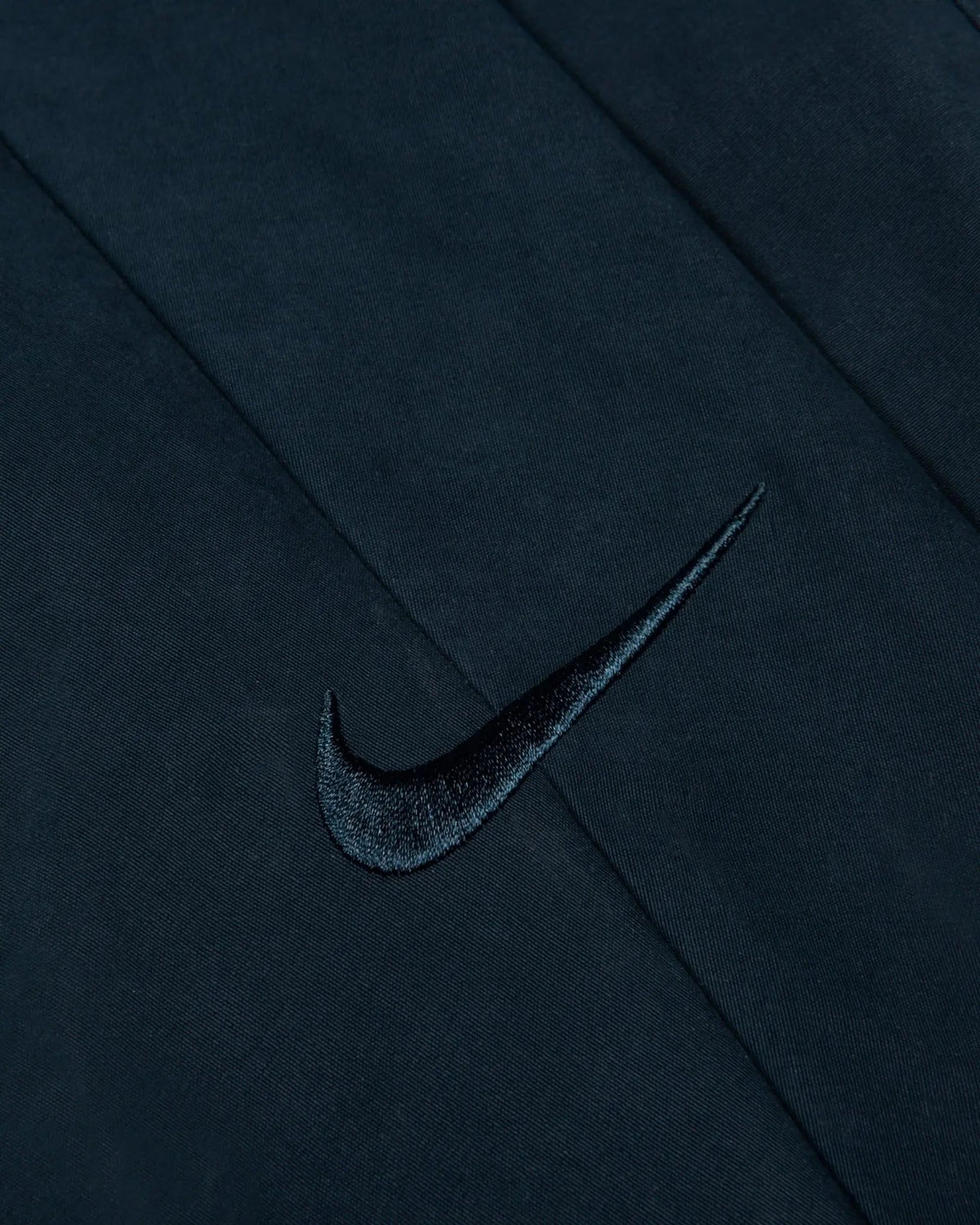 Close-up of the embroidered Nike Swoosh on the Patta x Nike NRG Track Jacket in Deep Ocean.