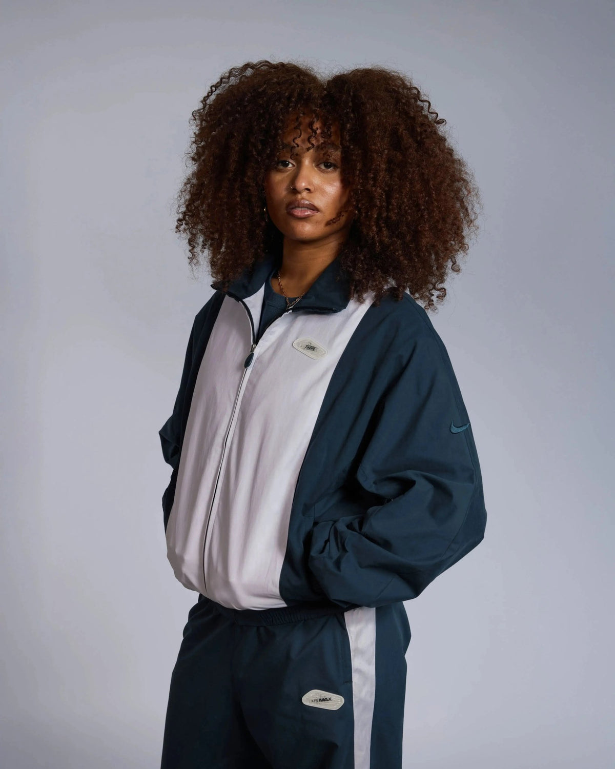 Model wearing the Patta x Nike NRG Track Jacket in deep ocean blue and white.