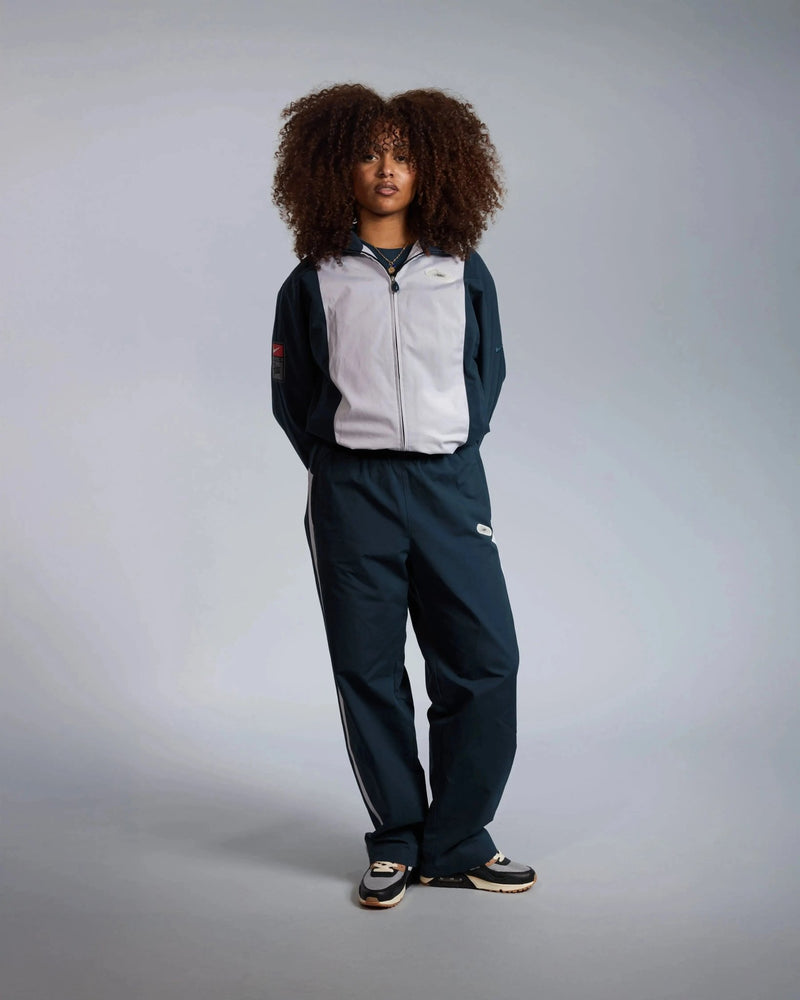 Model wearing the Patta x Nike NRG track jacket in deep ocean and white with matching track pants.
