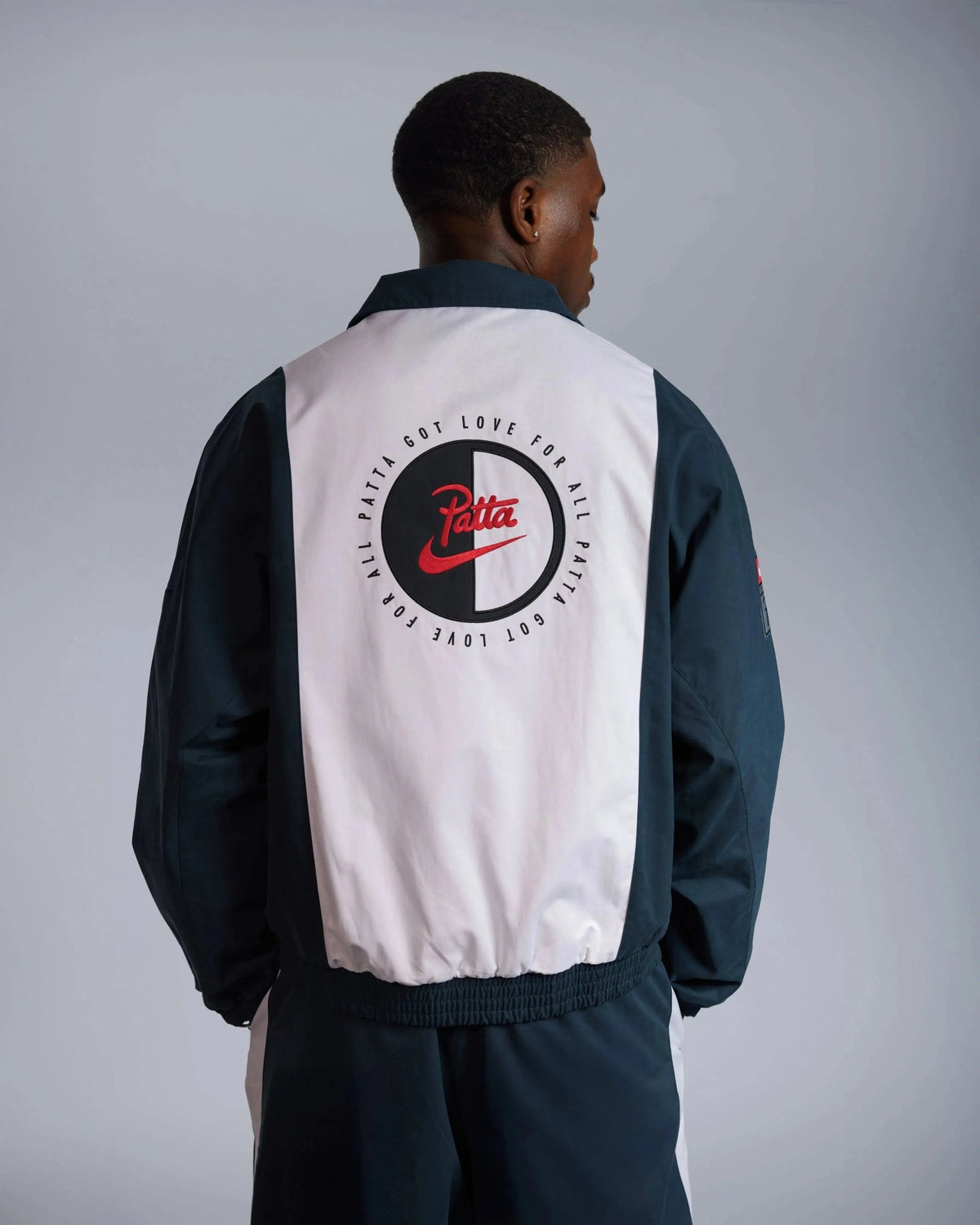 Back view of the Patta x Nike NRG Track Jacket in deep ocean and white with embroidered circular back graphic.
