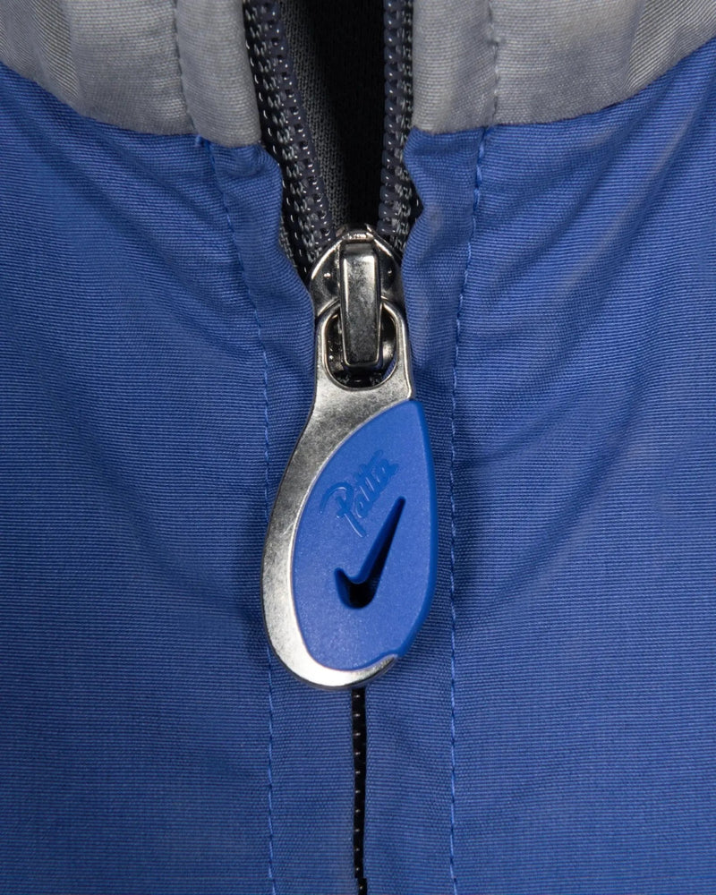 Close-up of the blue and silver custom zipper puller on the Patta x Nike NRG Track Jacket.