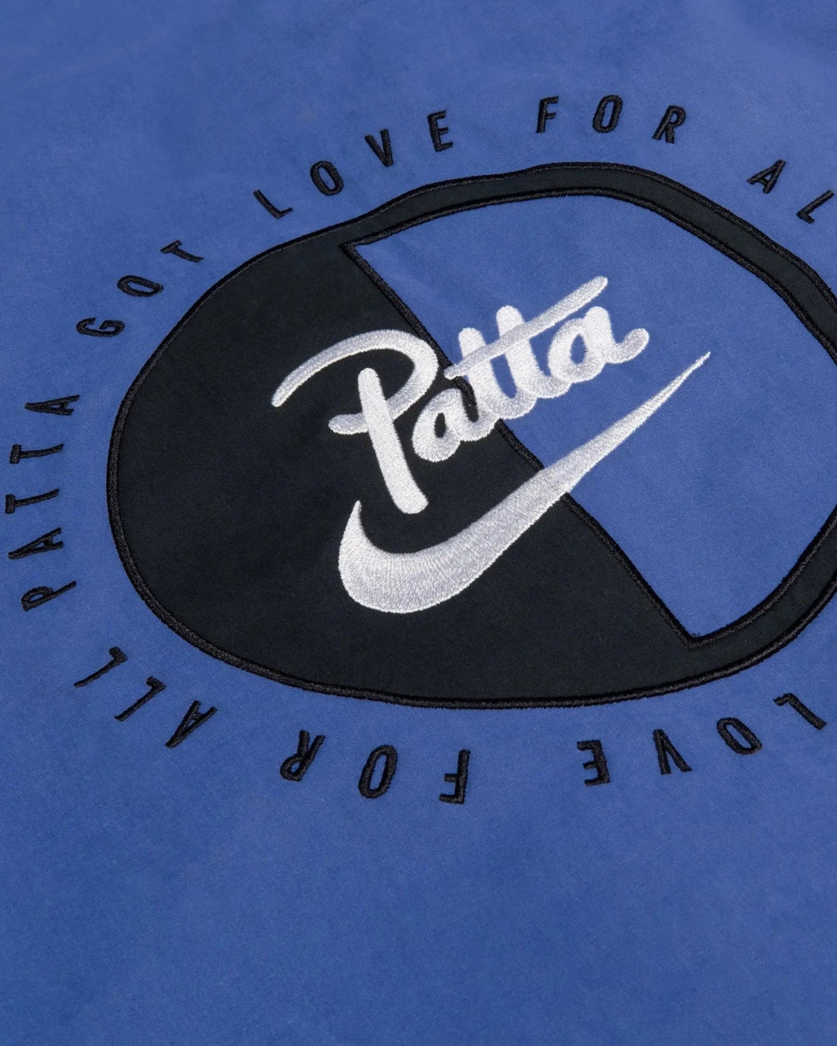 Embroidered Patta x Nike logo patch detail on the sapphire blue NRG Track Jacket.