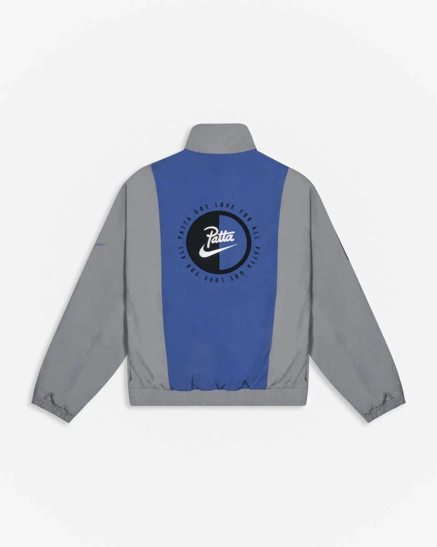 Back view of Patta x Nike NRG Track Jacket in Particle Grey and Sapphire with circular logo applique.