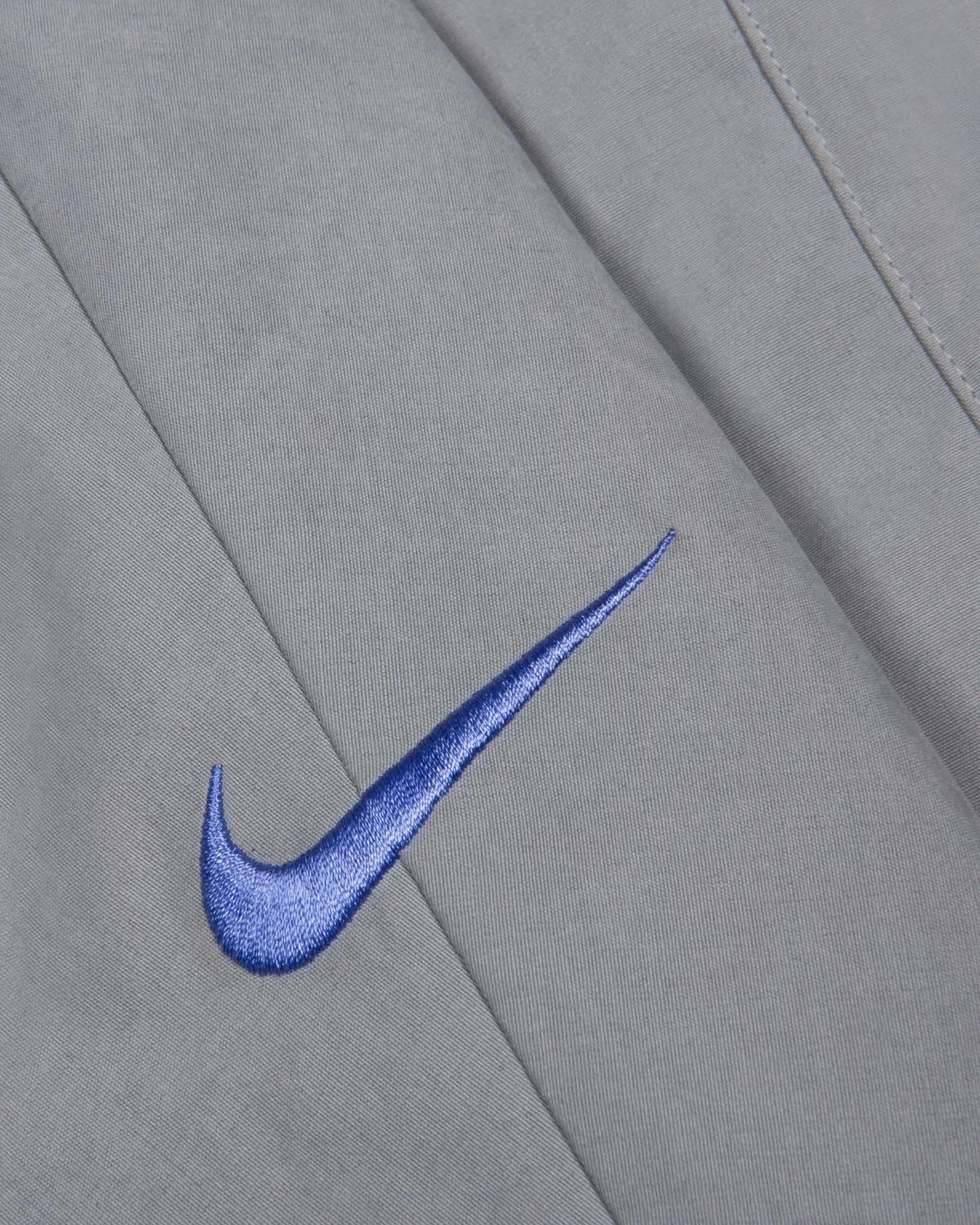 Embroidered sapphire blue Nike Swoosh on the Patta x Nike NRG Track Jacket in Particle Grey.