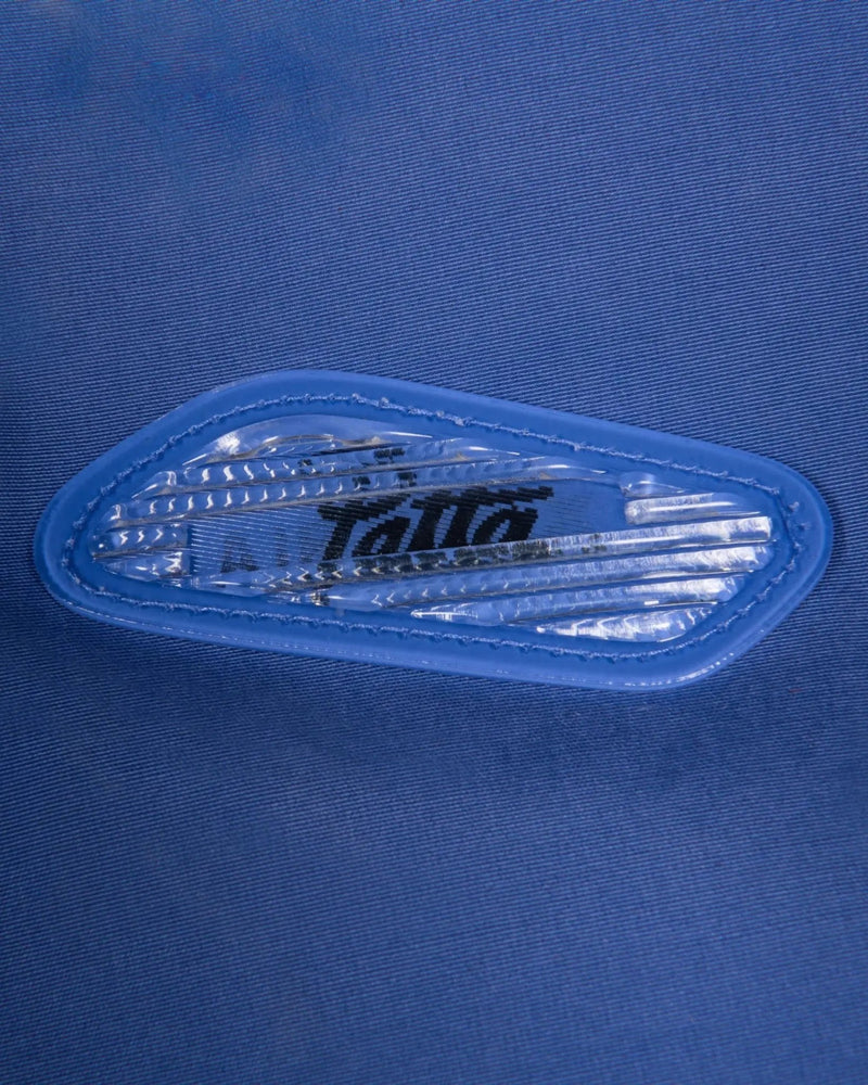 Close-up of the lenticular Air Max badge on the sapphire blue Patta x Nike NRG Track Jacket.