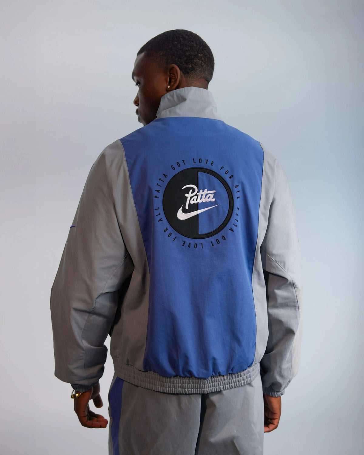 Back view of the Patta x Nike NRG Track Jacket in particle grey and sapphire blue with back graphic.