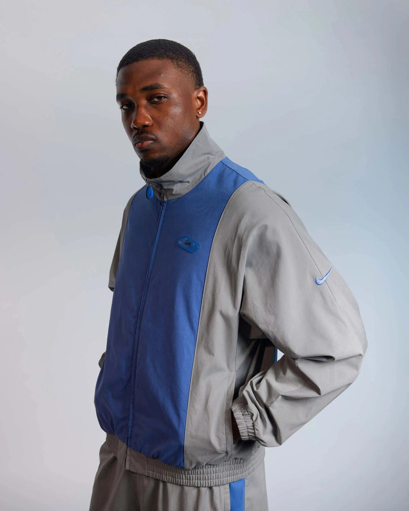 Patta x Nike NRG Track Jacket in particle grey and sapphire blue worn by a model.