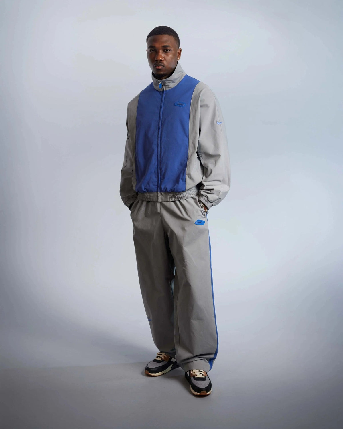 Model wearing the particle grey and sapphire Patta x Nike NRG track jacket with matching track pants.