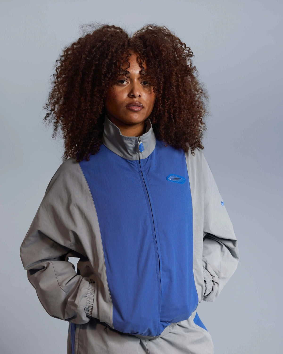 Model wearing the Patta x Nike NRG Track Jacket in particle grey and sapphire blue.