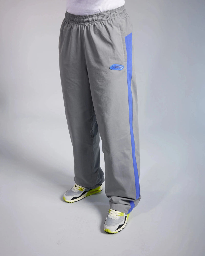 Patta x Nike NRG track pants in particle grey with sapphire blue side stripes worn by a model.