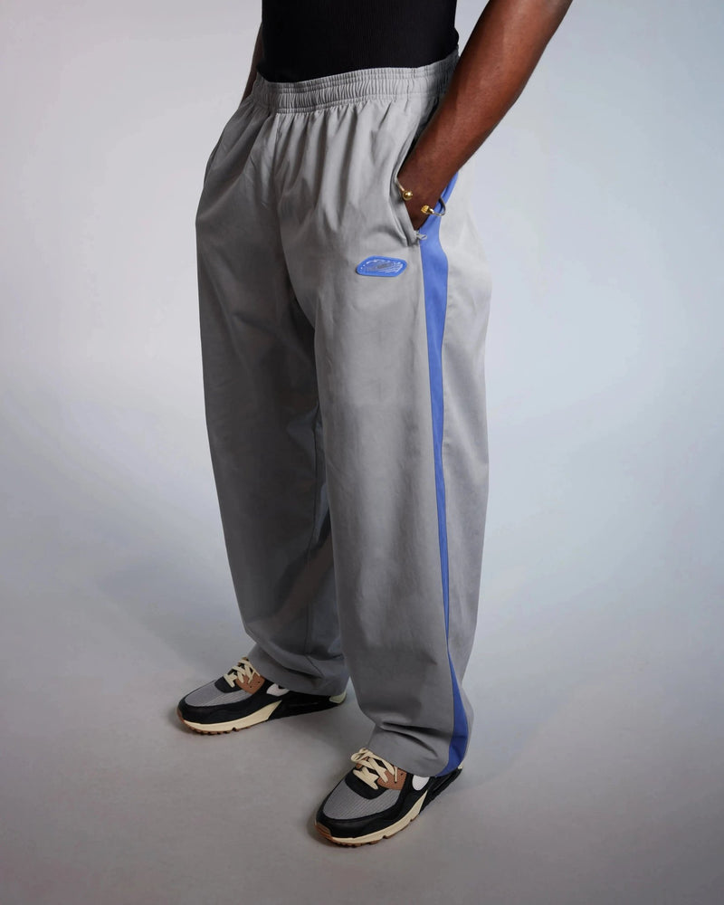 Patta x Nike NRG track pants in particle grey with sapphire blue stripe on a model.