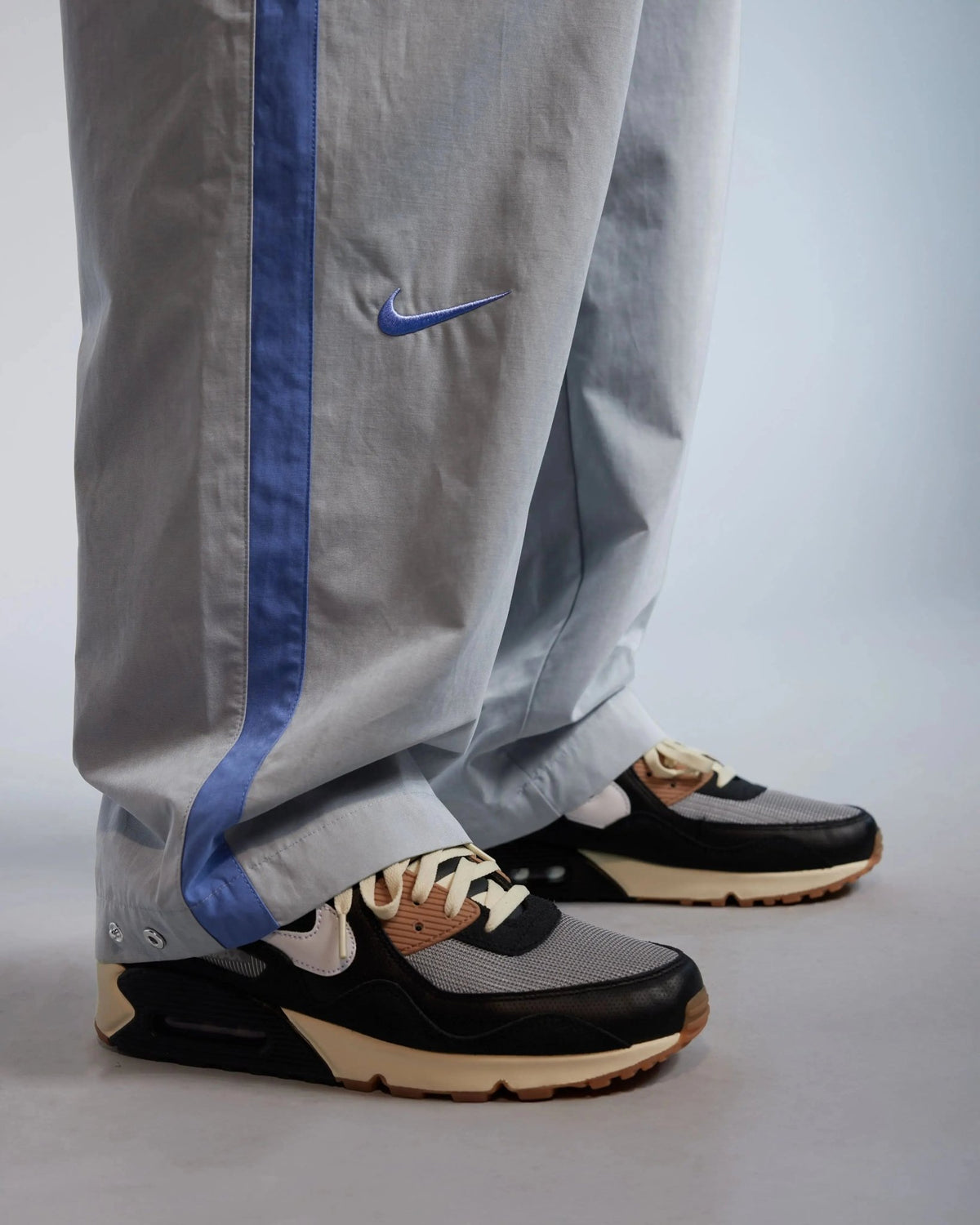 Close-up of Patta x Nike NRG track pants in particle grey with sapphire blue stripe and embroidered Swoosh.