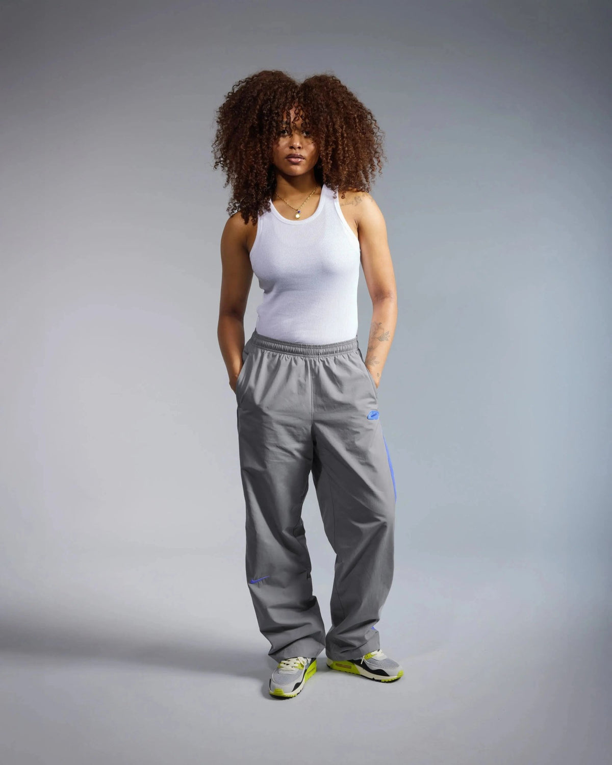 Model wearing Patta x Nike NRG track pants in particle grey and sapphire accents.
