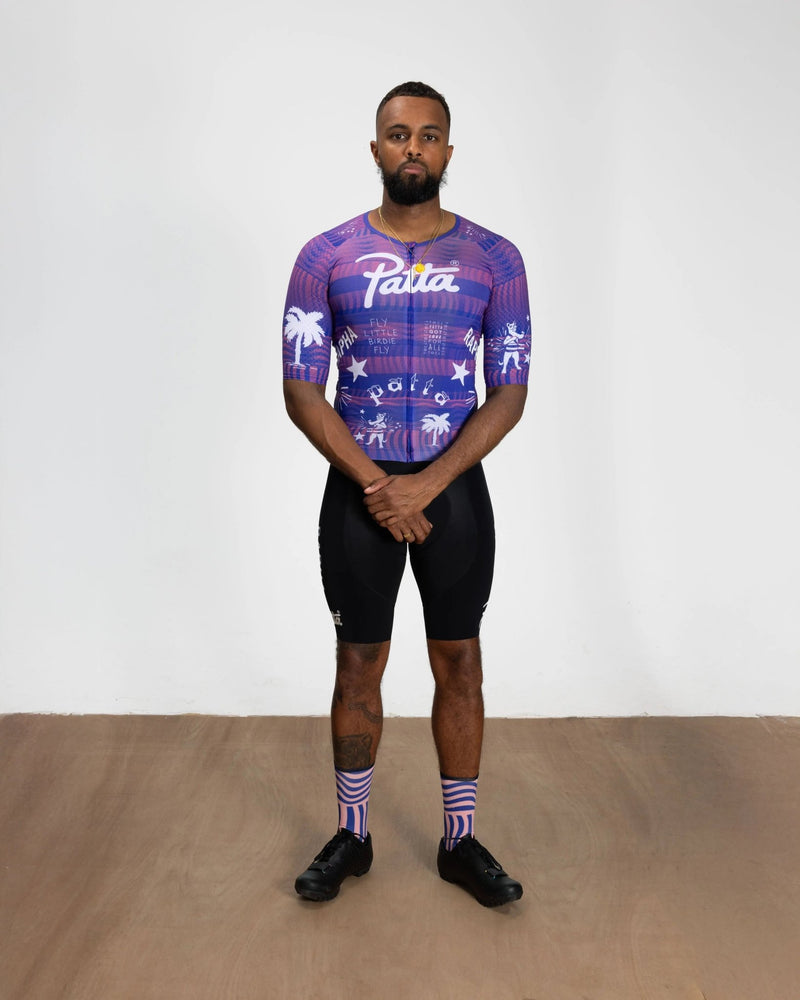 Model wearing the Patta x Rapha Men's Pro Team Aero Jersey in flamingo pink and royal blue.