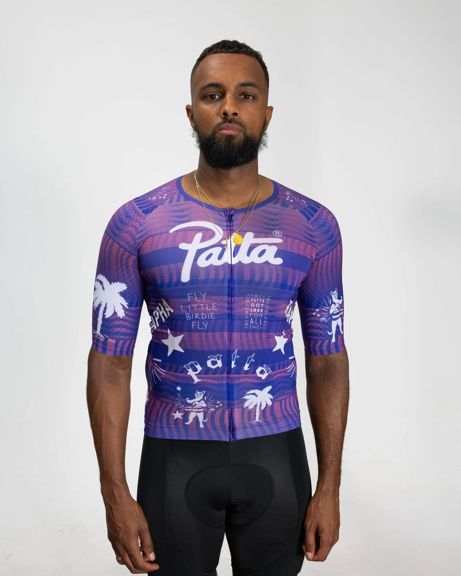 Front view of a model wearing the Patta x Rapha Pro Team Aero Jersey in flamingo pink and royal blue.