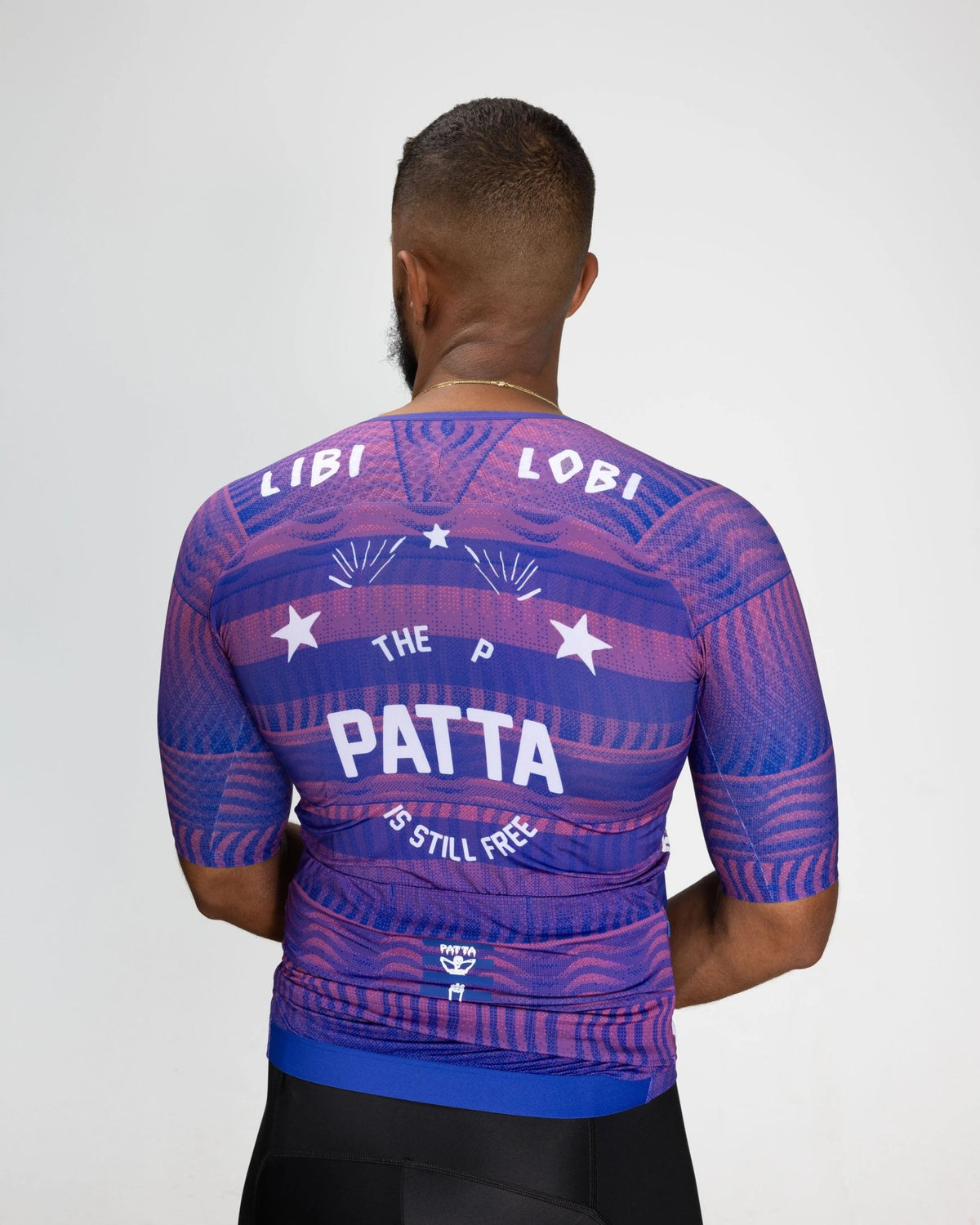 Back view of model wearing the Patta x Rapha Pro Team Aero Jersey in flamingo pink and royal blue.