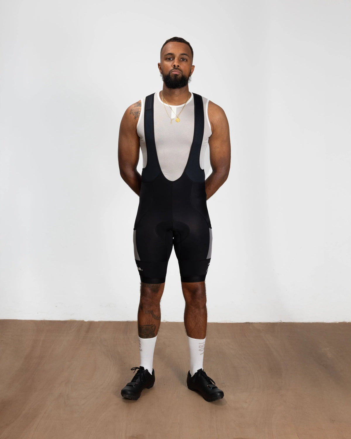 Model wearing black Patta x Rapha Pro Team cargo bib shorts paired with a white sleeveless base layer.