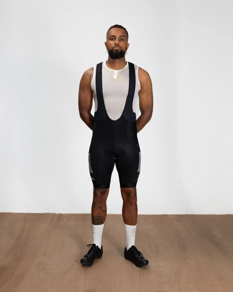 Model wearing black Patta x Rapha Pro Team cargo bib shorts paired with a white sleeveless base layer.