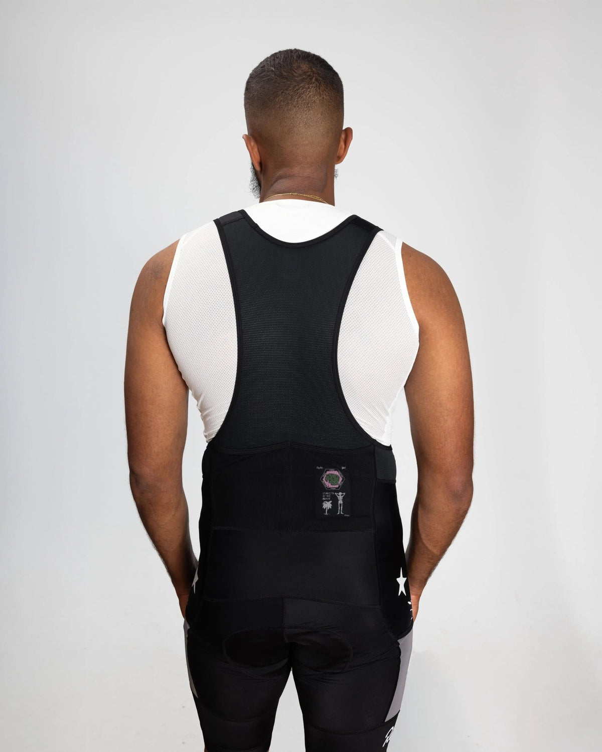 Rear view of a model wearing Patta x Rapha Pro Team Cargo Bib Shorts in black and stone.