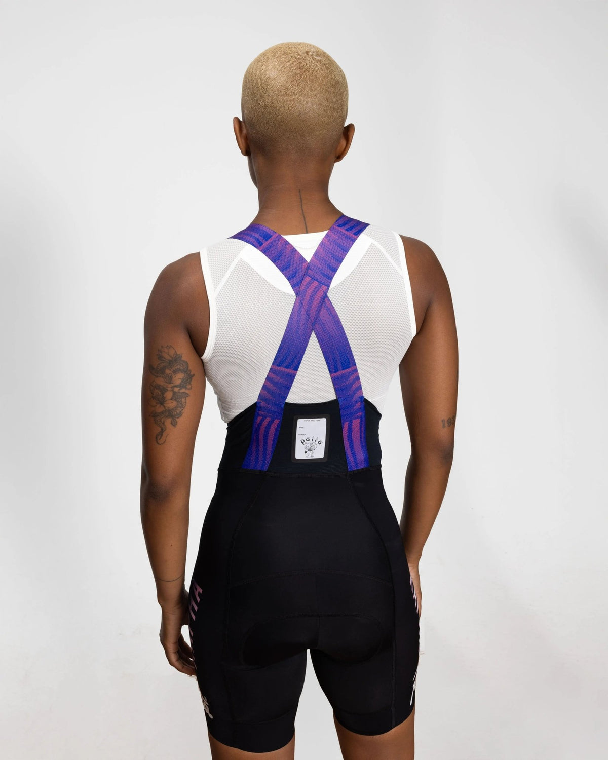 Back view of model wearing Patta x Rapha Women's Pro Team bib shorts with patterned crossover straps.