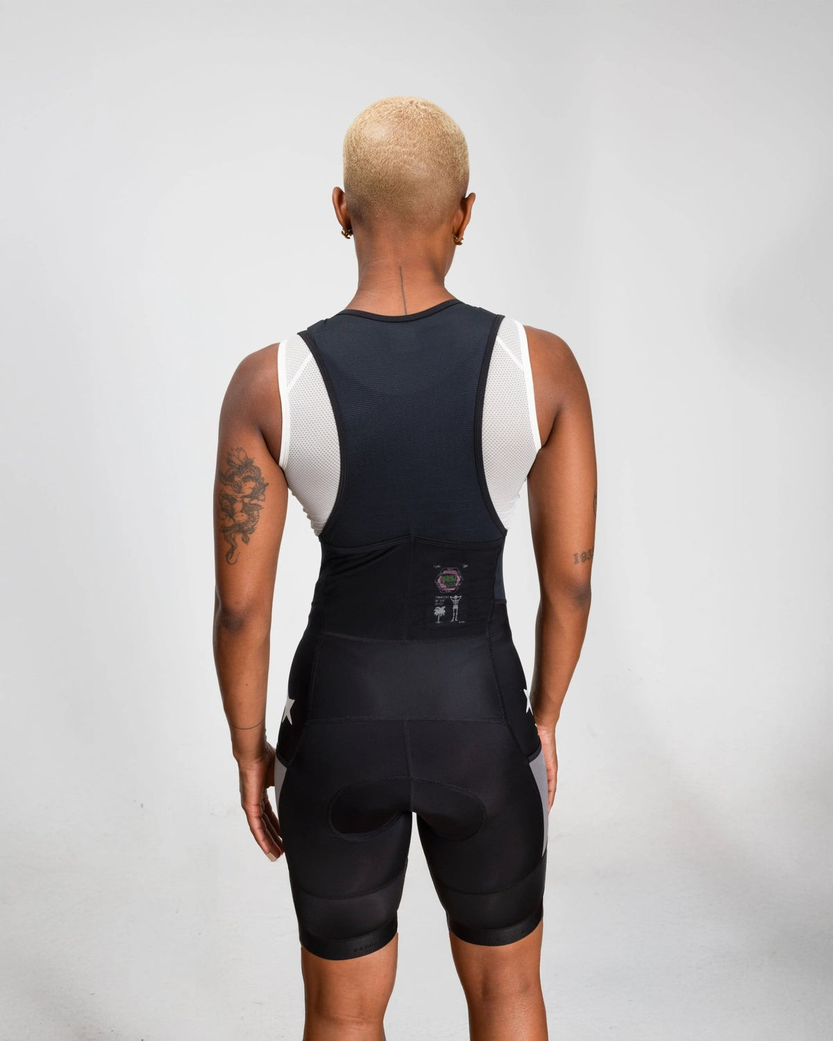 Back view of model wearing Patta x Rapha Women's Pro Team Cargo Bib Shorts in black and stone.