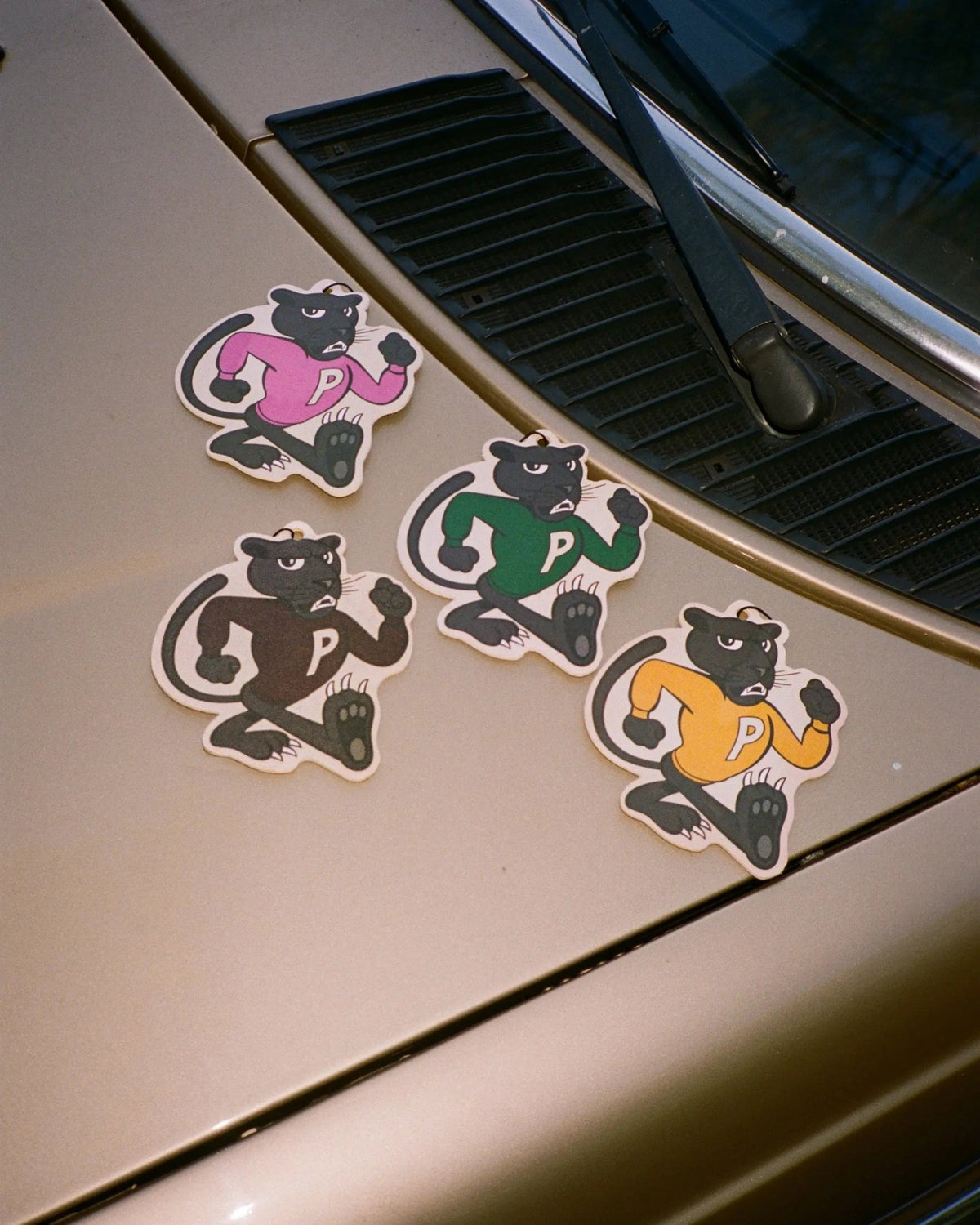Patta Panther air fresheners in four colorful jersey designs displayed on a vintage car hood.